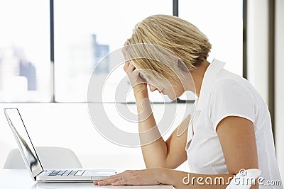 Frustrated Businesswoman Sitting At Desk In Office Using Laptop Stock Photo