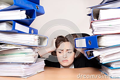 Frustrated businesswoman with stack of folders Stock Photo
