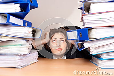 Frustrated businesswoman with stack of folders at office Stock Photo