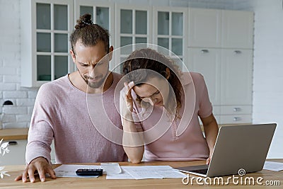 Frustrated concerned millennial married couple calculating overspend budget Stock Photo