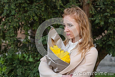 Frustrated disgruntled red-haired woman with bouquet of flowers arms crossed. Sad girl waits outside. Vertical frame Stock Photo