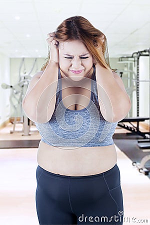 Frustrated fat woman standing at gym Stock Photo