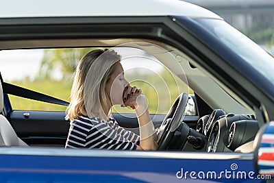 Frustrated female driver sit inside car with chin on hands scared to drive after vehicle accident Stock Photo