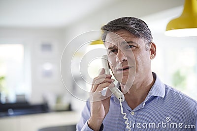 Frustrated Mature Man Receiving Sales Call At Home Stock Photo