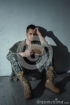 Frustrated military veteran looking at photo Stock Photo