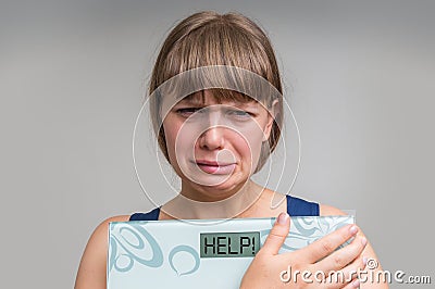 Frustrated overweight woman holding digital scales with HELP! Stock Photo