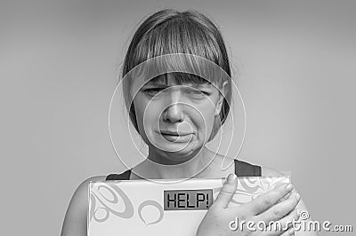 Frustrated overweight woman holding digital scales with HELP! Stock Photo