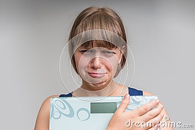 Frustrated overweight woman with scales Stock Photo