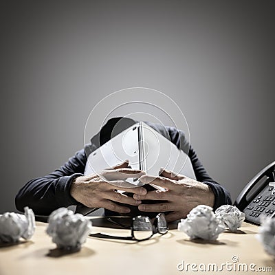 Frustrated and overworked man burying his head under a laptop computer Stock Photo
