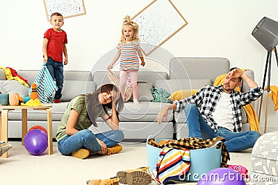 Frustrated parents and their mischievous children in room Stock Photo