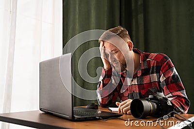 Frustrated Photographer off loading files on laptop. Checking photos working at modern office. editing his images on Stock Photo