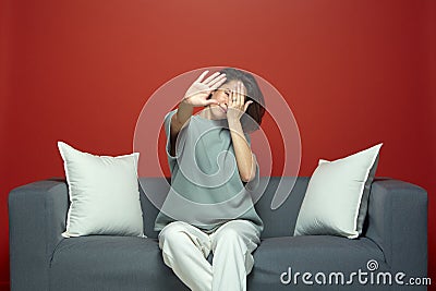 Young girl close eyes by hands, show stop gesture dont want to see disgraceful or scary movie or series sitting on couch Stock Photo