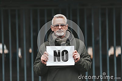 Frustrated senior man holding a stop sign. Protest of disgruntled mature person Stock Photo