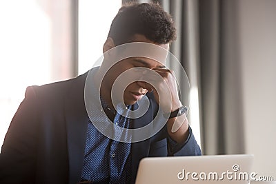 Frustrated stressed black businessman feel eye strain headache at work Stock Photo