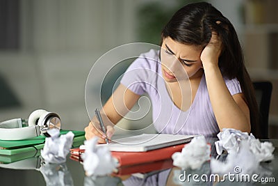 Frustrated student crumpling papers in the night Stock Photo