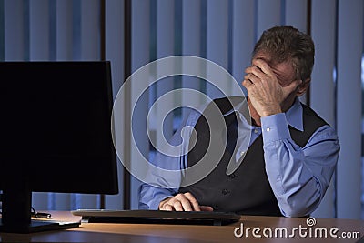 Frustrated tired businessman sitting in a dark blue office Stock Photo