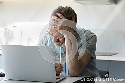 Frustrated tired senior man touching head at laptop Stock Photo