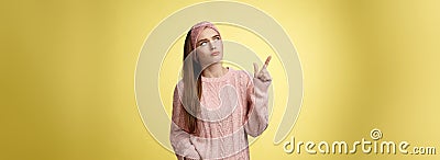 Frustrated upset, gloomy cute young woman frowning making disappointed grimace pointing, looking upper left corner Stock Photo