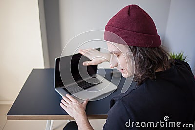 Frustrated user closes the laptop. A young programmer in the workplace has problems at work Stock Photo