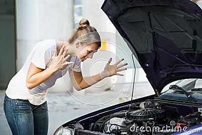 Frustrated Woman Looking At Broken Down Car Engine Stock Photo