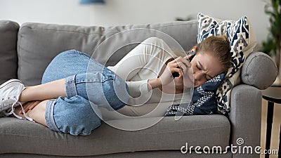 Frustrated woman lying on couch, talk on phone, hearing bad news Stock Photo