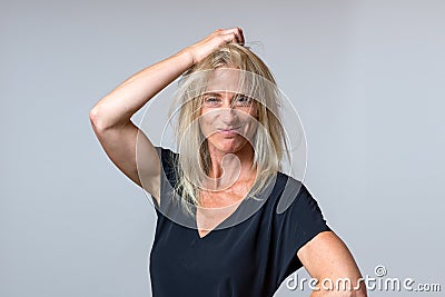Frustrated woman tearing at her long blond hair Stock Photo