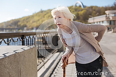 Frustrated woman worrying about her back on the street Stock Photo