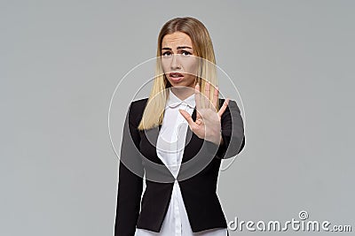 A frustrated young business woman frowns her eyebrows and shows a sign of refusal with her hand, asks to stop Stock Photo