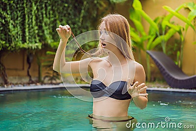 Frustrated young woman having a bad hair in the pool. Due to the fact that chemicals in the pool Stock Photo