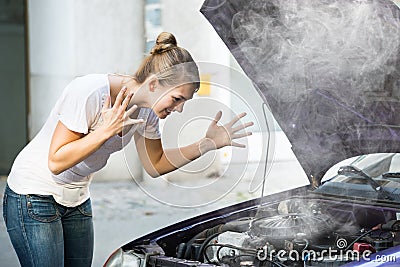 Woman Looking Under The Hood Of Breakdown Car Stock Photo