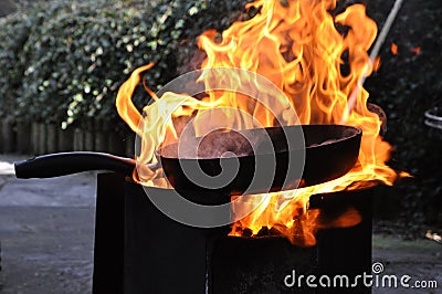 Frying pan on open fire place with burning flames Stock Photo