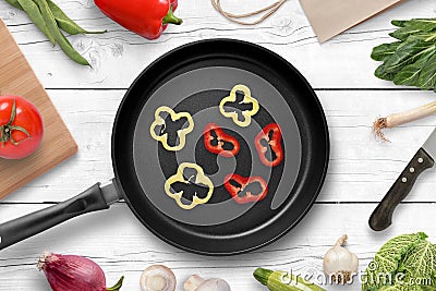 Frying a piece of pepper in a pan for preparing a delicious meal. Fresh vegetables on the white wooden kitchen table Stock Photo