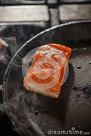 Frying salmon in black pan Stock Photo