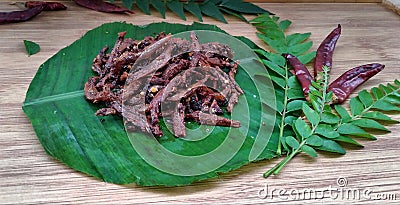 Frying small spicy sprats in banana leaf Stock Photo