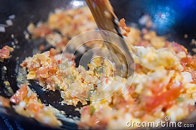Frying and stirring eggs and traditional pico de gallo in a frying pan Stock Photo