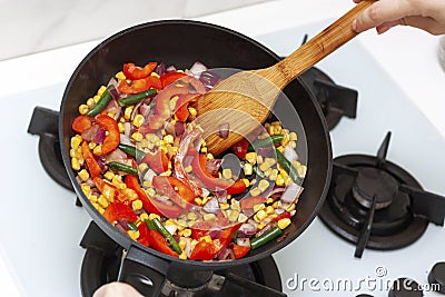 Frying vegetables on a pan on gas stove Stock Photo