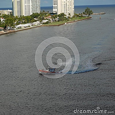 A US Coast Guard boat escorts a cruise ship into or out of port from the ocean channel Editorial Stock Photo