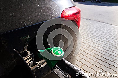 Fuel nozzle with new EU labeling circle gasoline type filling car tank from petrol station dispenser, black car Stock Photo