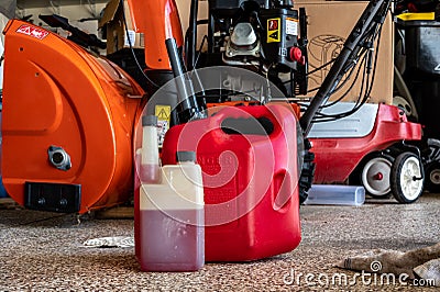 Fuel stabilizer container for long term storage of gas in front of a portable canister and snow blower Stock Photo