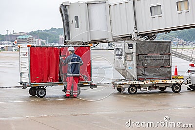 Airport baggage handler checks on a baggage container at Fukuoka airport in Japan Editorial Stock Photo