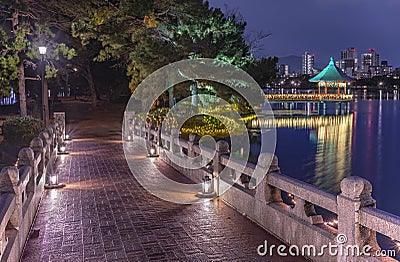 Kangetsu bridge lighted-up crossing the pond of Ohori Park with Ukimi-do Pavilion in background. Editorial Stock Photo