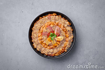 Ful Medames or Fava Beans in black bowl at grey backdrop. Foul Mudammas is a Egyptiancuisine breakfast dish Stock Photo