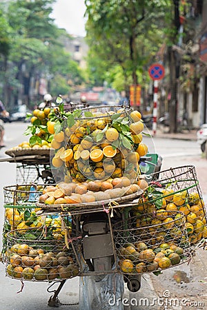 Full basket of orange fruit on vendor bike on Hanoi street, Vietnam Stock Photo