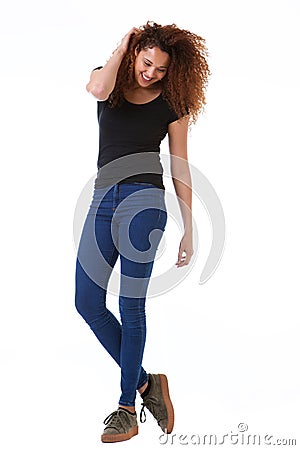Full body happy young woman with hand in curly hair standing against isolated white background Stock Photo