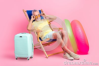 Full body length cadre of retired man lying sunbed mallorca country sunny weather touch his glasses isolated on pink Stock Photo