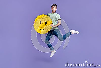 Full body photo of attractive young guy jump holding smile emoji pinata optimist wear trendy gray look isolated on Stock Photo