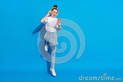 Full body photo of cheerful energetic girl jump enjoy listen music headset smartphone wear style stylish trendy white t Stock Photo