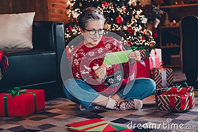 Full body photo of cute alone funny grandmother in christmas sweater stay home and unpacking gifts reading letters Stock Photo