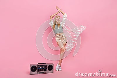 Full body photo of millennial blond lady dance near boombox wear top cape shorts sneakers isolated on pink background Stock Photo