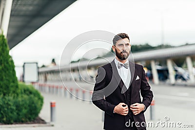 Full body picture of a young business man closing his jacket while looking at the camera Stock Photo